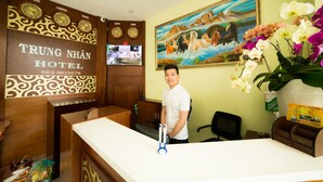 A hotel reception desk with clocks, a painting, and orchids. - Trung Nhan Hotel (Cam Ly - Da Lat)