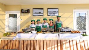 A buffet setup with multiple food stations and staff in green aprons. - Trung Nhan Hotel (Cam Ly - Da Lat)
