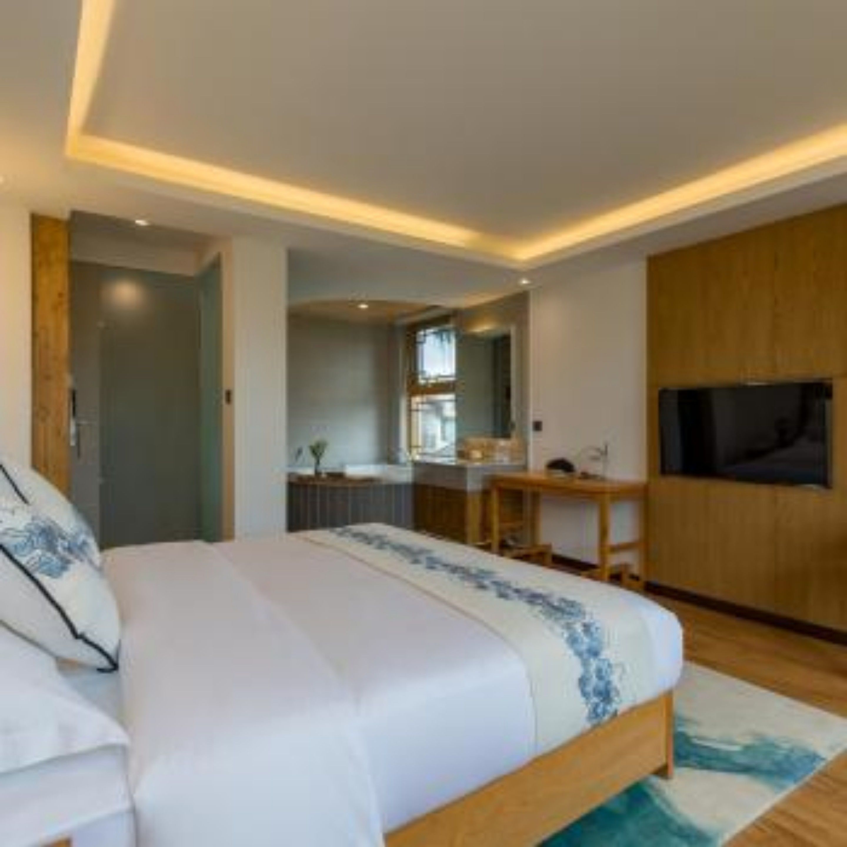 Une chambre à coucher moderne avec un grand lit, un bureau et un téléviseur.