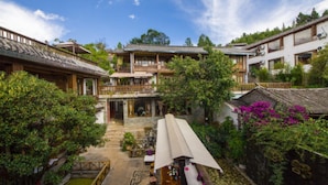 A traditional courtyard with wooden buildings, a central open space, and surrounding greenery. - Floral Hotel Lijiang Banshanyunfu (Lijiang)