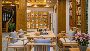 A wooden interior with a dining area, a wall of wine bottles, and a staircase. - Floral Hotel Lijiang Banshanyunfu (Lijiang)