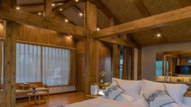 A wooden cabin-style bedroom with a large bed, a television, and a desk. - Floral Hotel Lijiang Banshanyunfu (Lijiang)