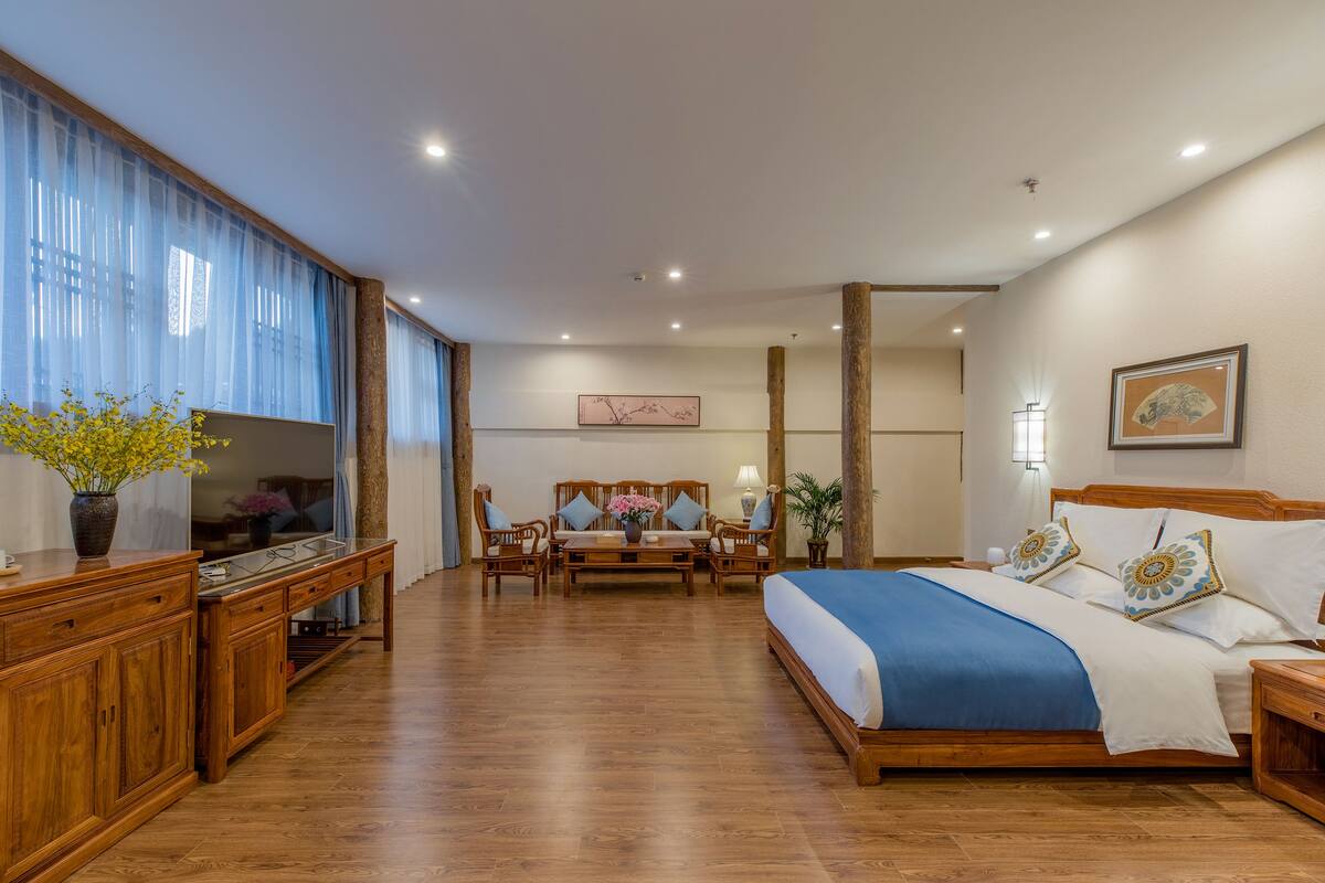 Een hotelkamer met een houten bed, een bureau met een computer, een bank en een salontafel.