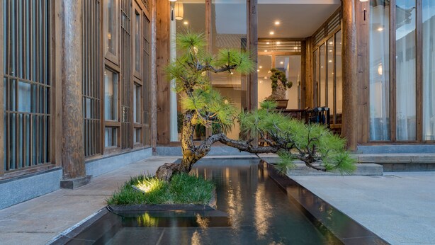 Un interior japonés tradicional con una fuente de agua, columnas de madera y una zona de recepción.