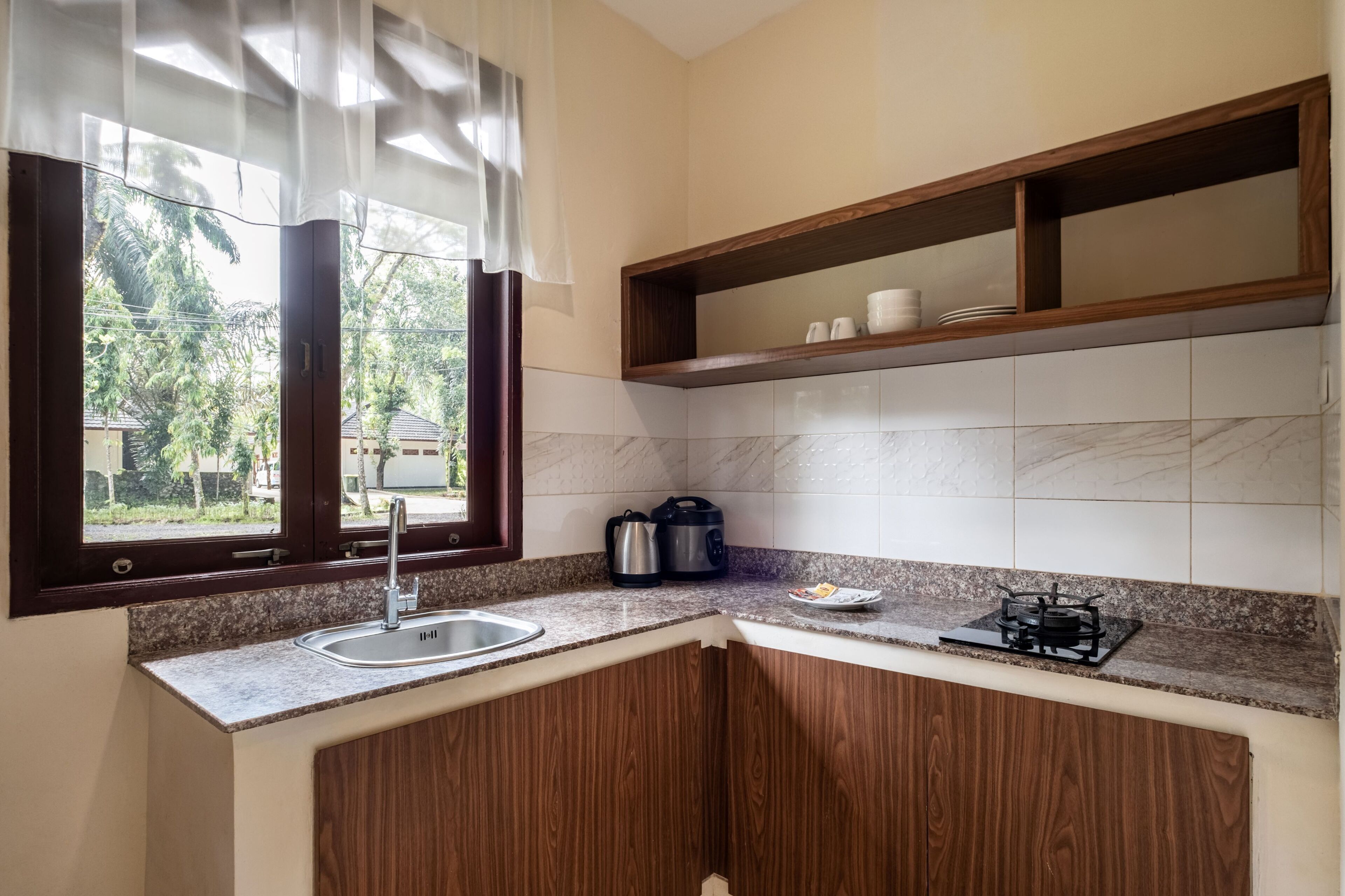 A kitchen with a sink, stove, and wooden cabinets.