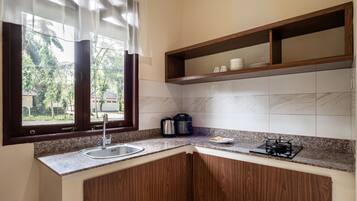 A kitchen with a sink, stove, and wooden cabinets.