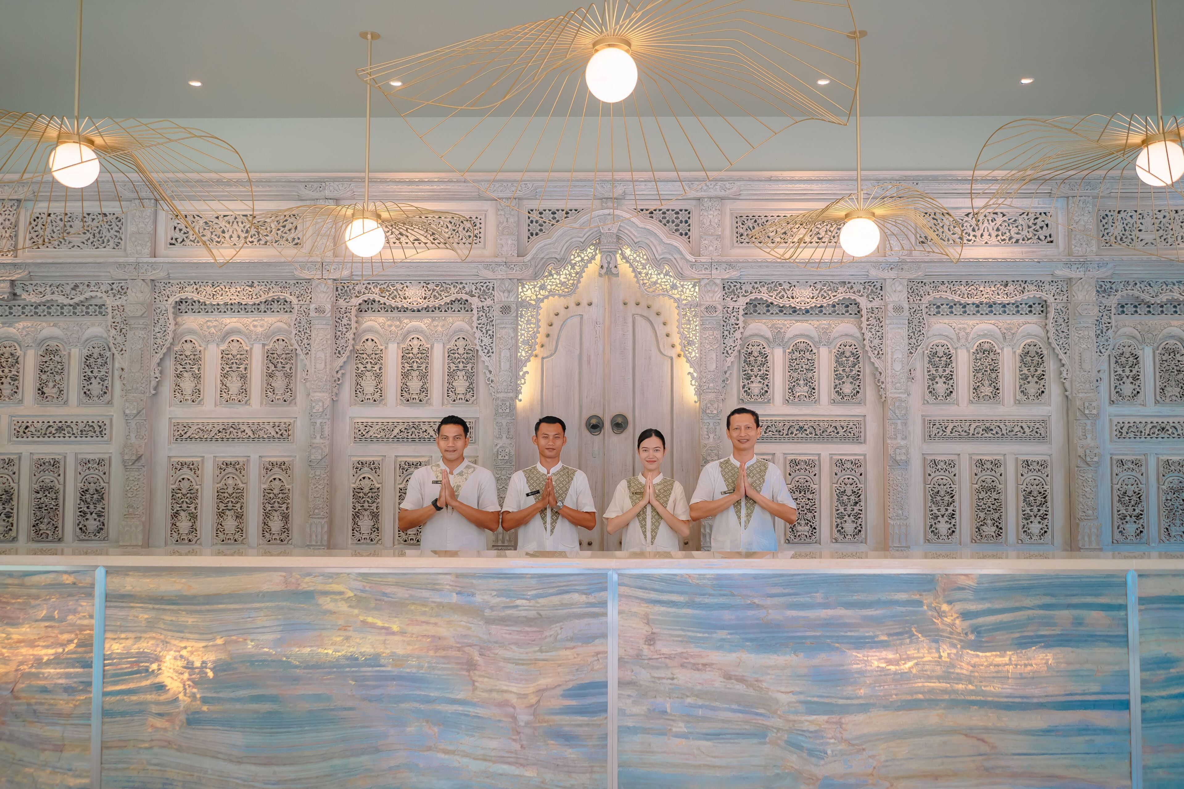 A group of people standing in front of a wall with intricate carvings and a large painting.