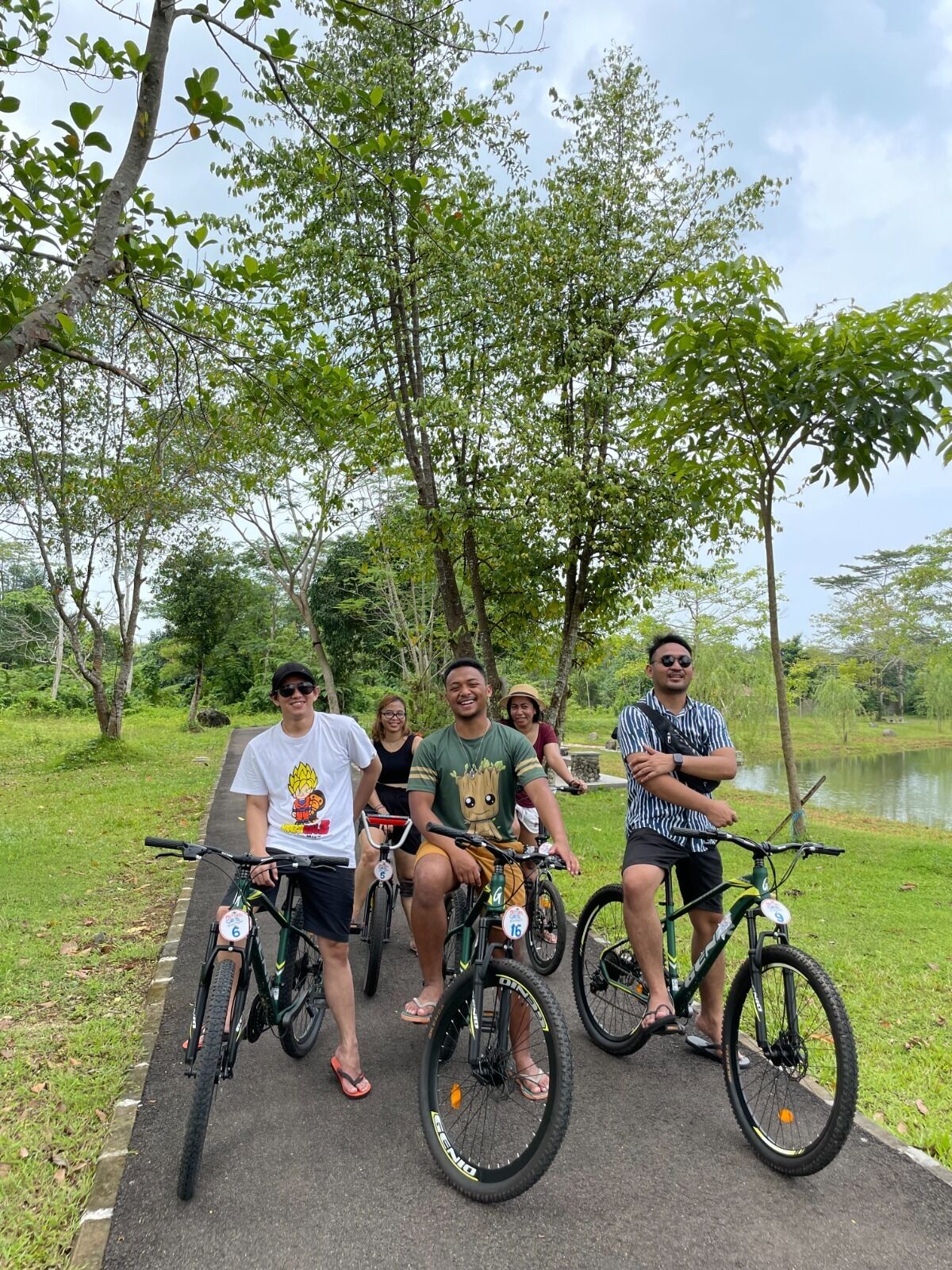 Un grupo de personas en bicicleta sobre un sendero pavimentado rodeado de vegetación.