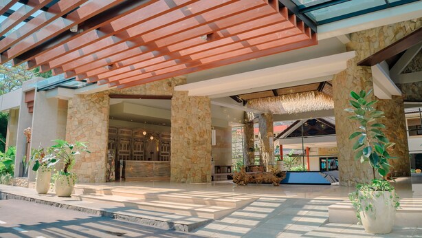 A spacious lobby with a modern design, featuring a stone column, a glass railing, and potted plants. - Mutiara Carita Cottages (Carita)