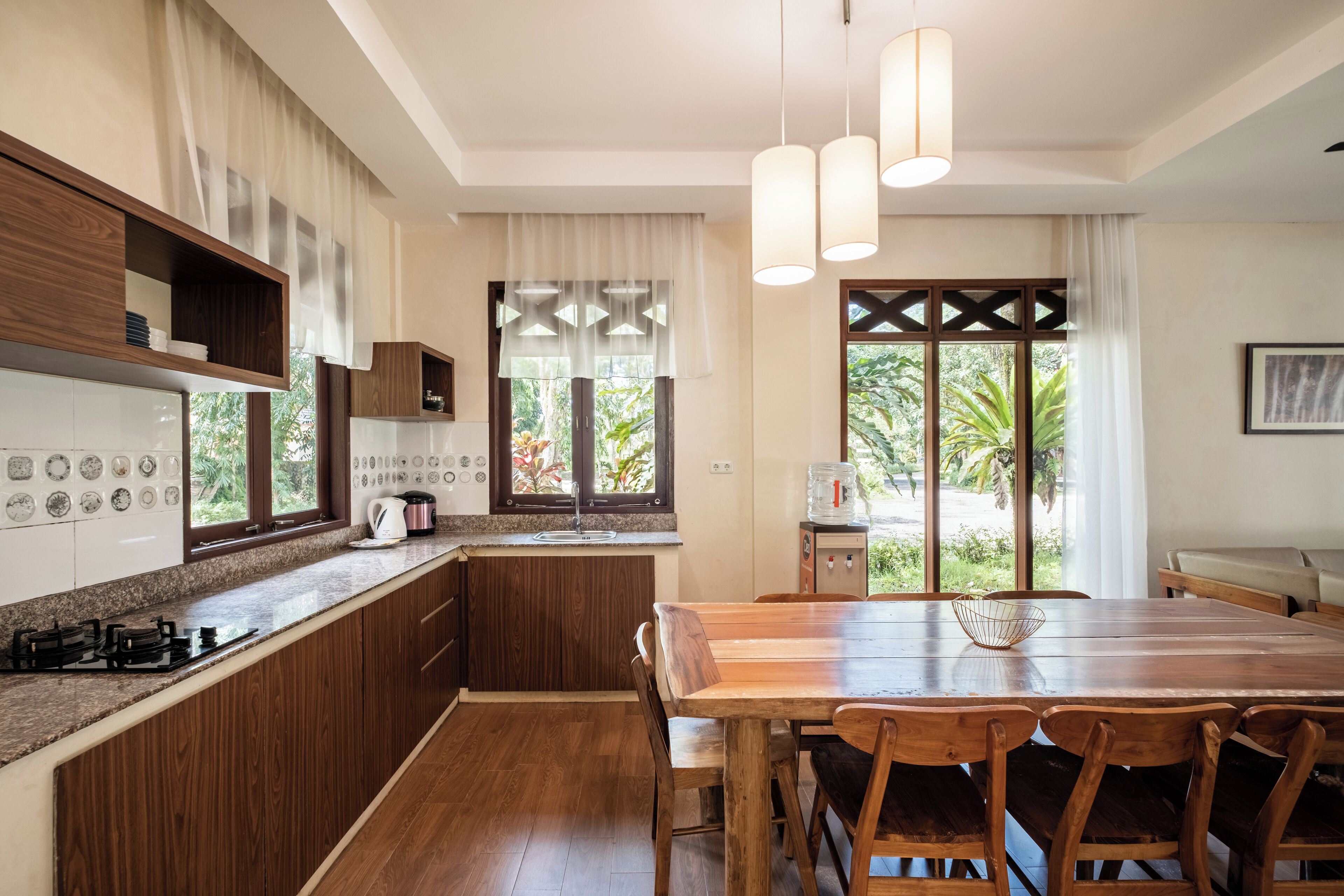 A modern kitchen with wooden cabinets, a granite countertop, and a dining area with a wooden table and chairs.