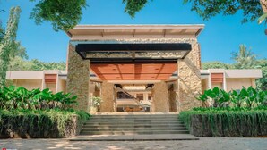 A modern building with a stone facade, a wooden overhang, and a staircase leading to a covered entrance. - Mutiara Carita Cottages (Carita)