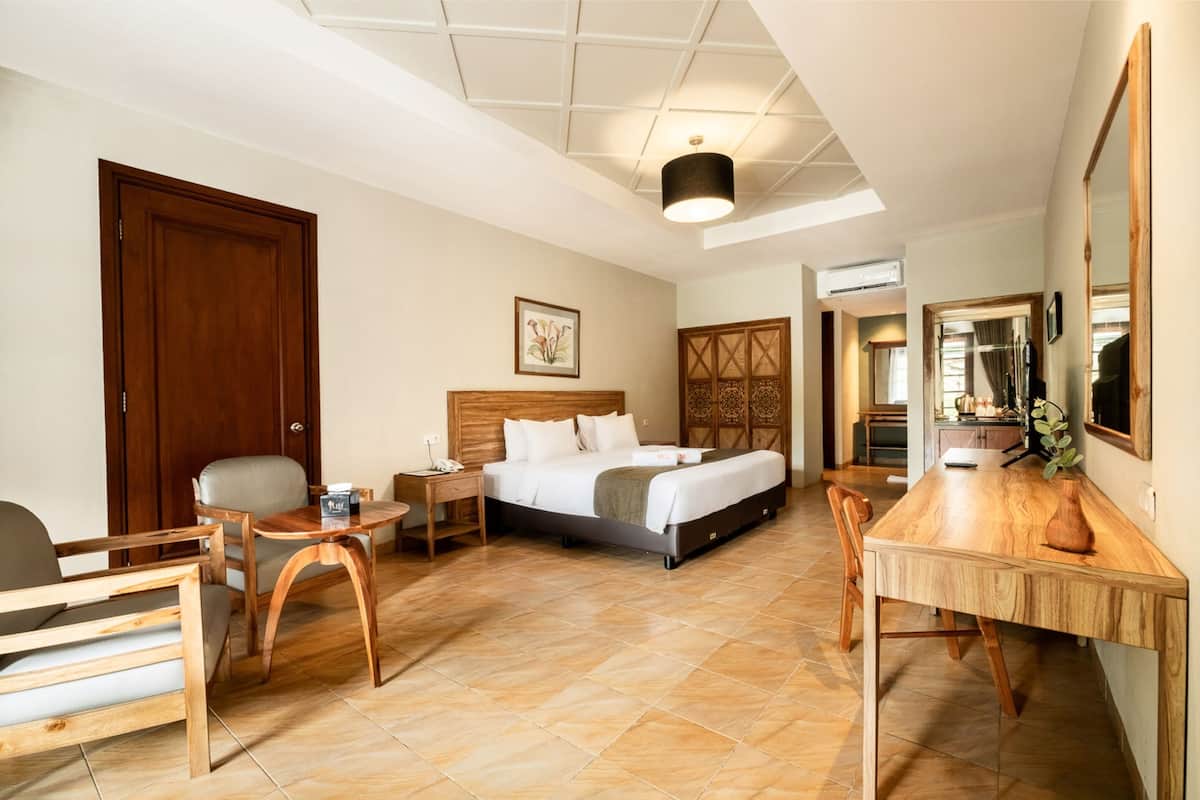 Ein Hotelzimmer mit Bett, Schreibtisch, Stuhl, kleinem Tisch und Spiegel.