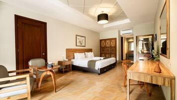Habitación de hotel con cama, escritorio, silla, mesita y espejo.
