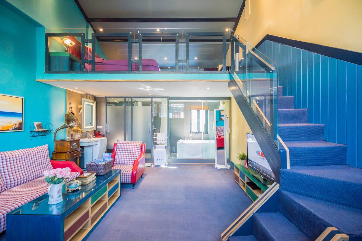 A modern interior with a loft bedroom, a staircase, and a living area with a sofa and a coffee table.