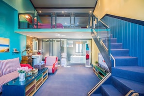 A modern interior with a loft bedroom, a staircase, and a living area with a sofa and a coffee table.