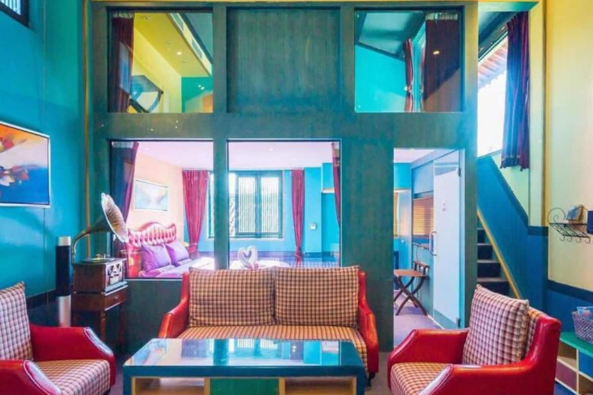 A spacious living area with a high ceiling, a central sofa, and red armchairs.