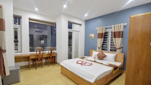 Une chambre à coucher avec un lit en bois, un bureau et des chaises, une fenêtre avec des rideaux et une porte.