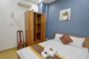 A hotel room with a bed, a wooden wardrobe, a chair, and a wall-mounted air conditioner. - So Ri Hotel (Quy Nhon)