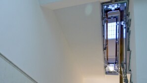 Un escalier étroit avec une rampe en bois menant à un palier.