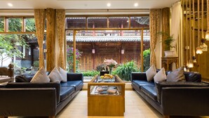 Un salon de style traditionnel, avec deux canapés placés face à face, une table basse en bois et une vue sur un jardin extérieur grâce à de grandes fenêtres.