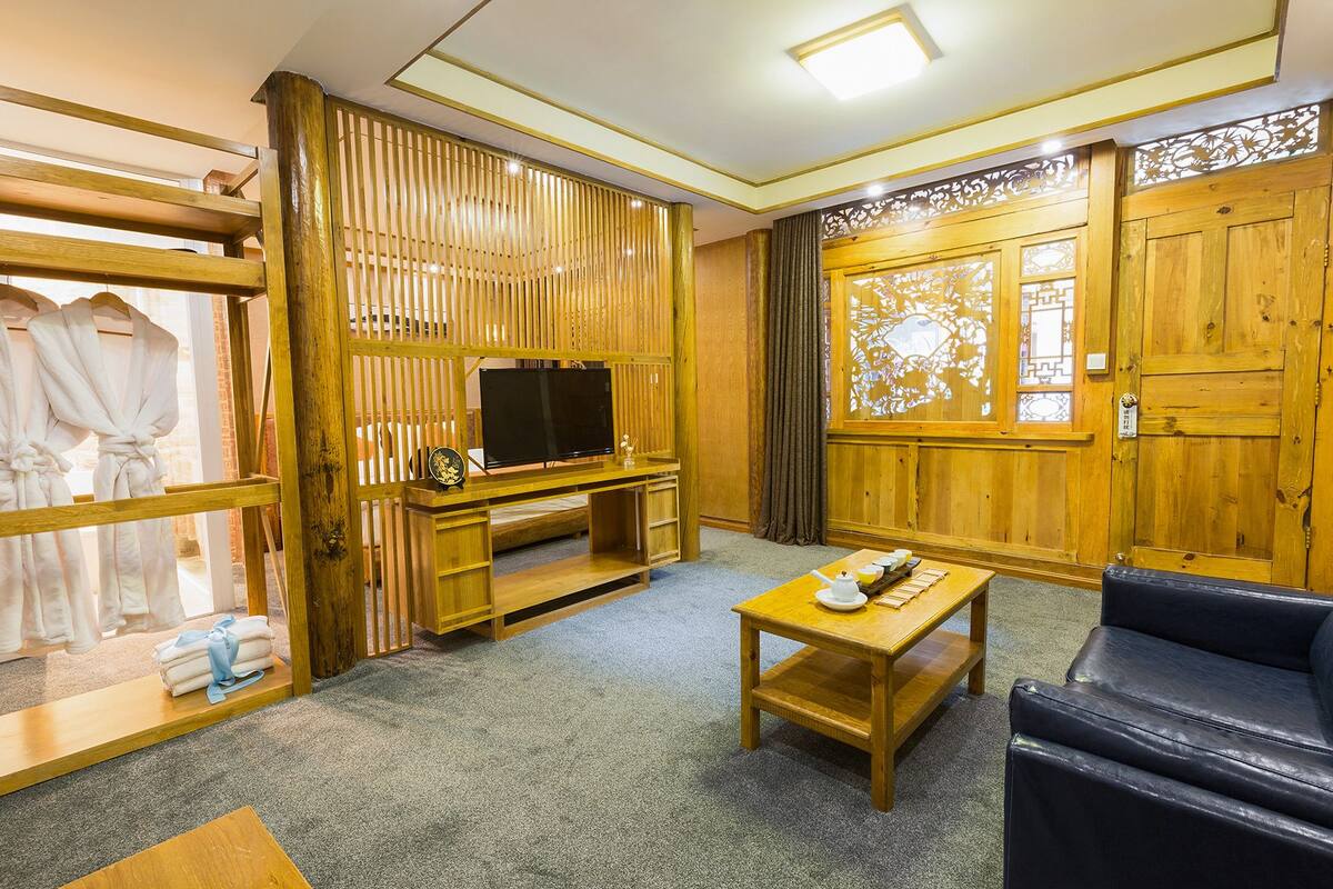 Een kamer met een houten tv-meubel, een bank en een tafel met dienblad.