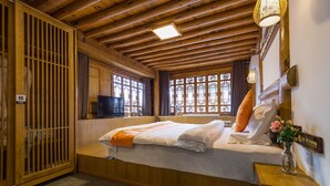 Une chambre avec un lit, une télévision et une fenêtre ornée de vitraux.