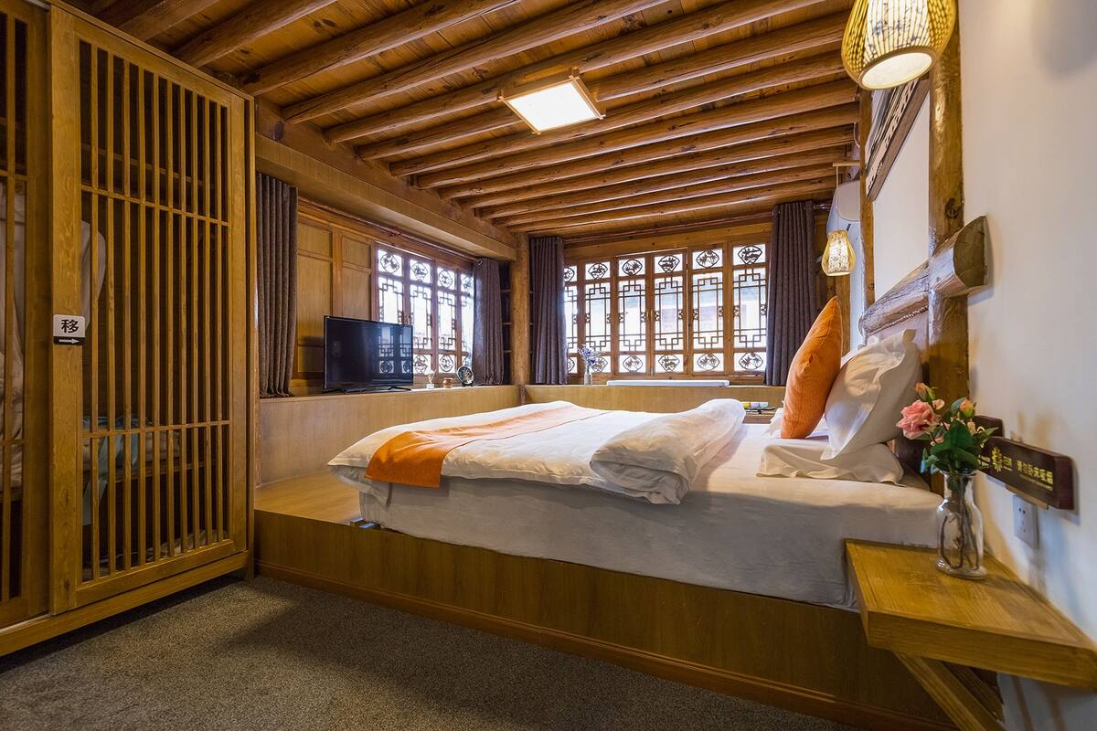 Een kamer met een bed, een televisie en een raam met decoratief glas.