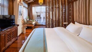 Una habitación tradicional con una cama grande, muebles de madera y televisión.