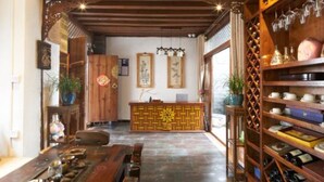 Un interior tradicional con una recepción, estantes de madera con botellas de vino y un comedor con una mesa larga.