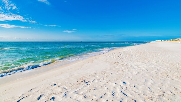 En strand med kristallklart blått vatten och en sandstrand.