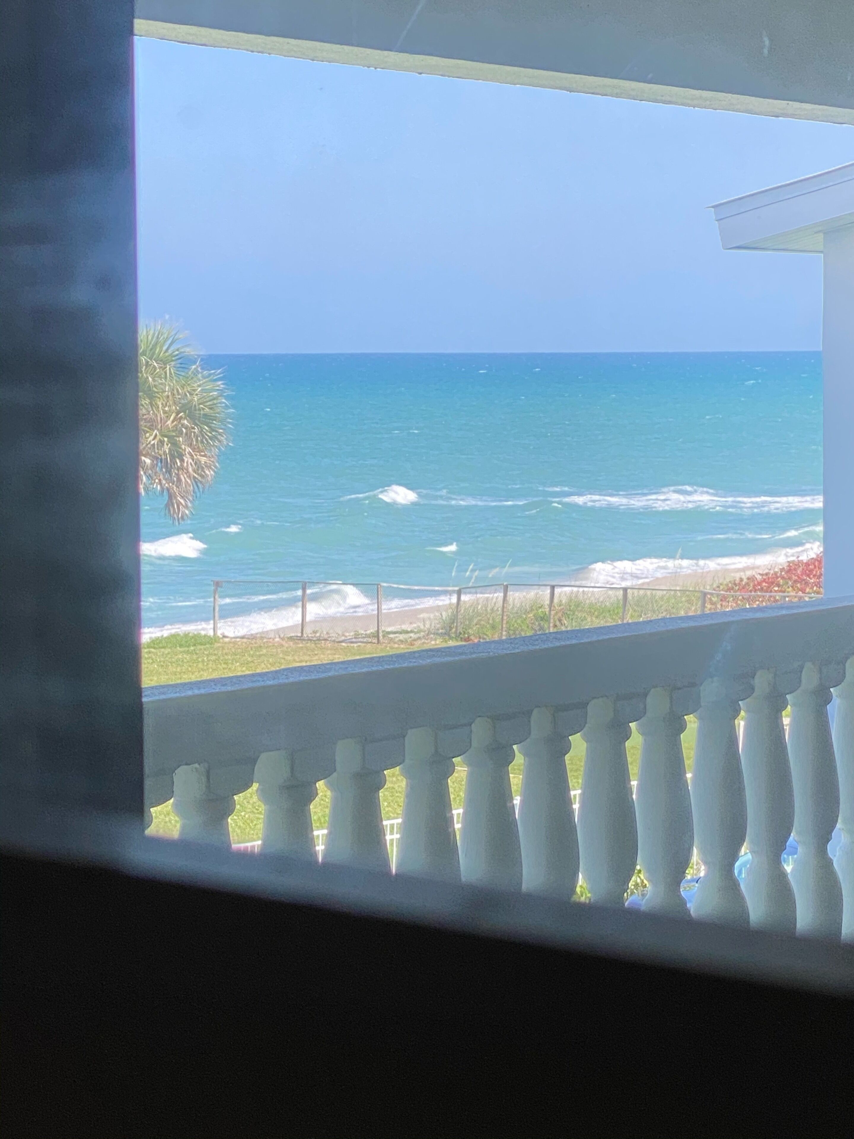 A view of the ocean from a balcony with a railing.
