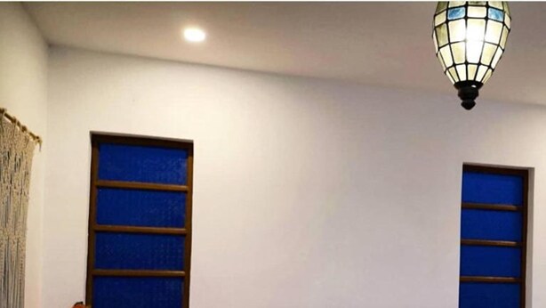 A neatly made bed with a patterned blanket, a bedside lamp, and a sign indicating the room number. - Balai Vittorio (Oton)