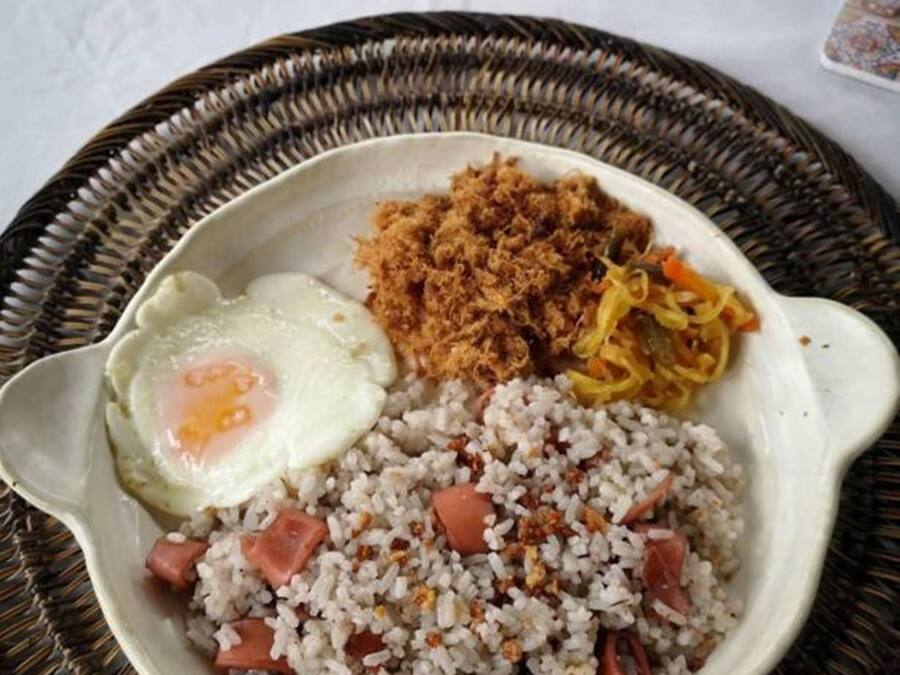 Une assiette de riz frit, d’un œuf au plat et d’oignons frits croustillants en accompagnement.
