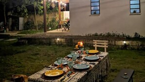 An outdoor dining area with a table set for four, surrounded by chairs, under string lights. - Balai Vittorio (Oton)