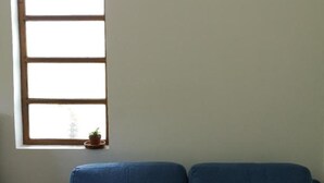 A room with a blue sofa, a window with a view, and a small potted plant on the windowsill. - Balai Vittorio (Oton)