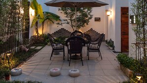 A courtyard with a traditional Asian-style roof, a table with chairs, and an umbrella. - Floral Hotel Wuzhen Ziyemusu (Jiaxing)
