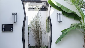 A narrow entrance with a traditional tiled roof, a black sign with white text, and two wall-mounted lanterns. - Floral Hotel Wuzhen Ziyemusu (Jiaxing)