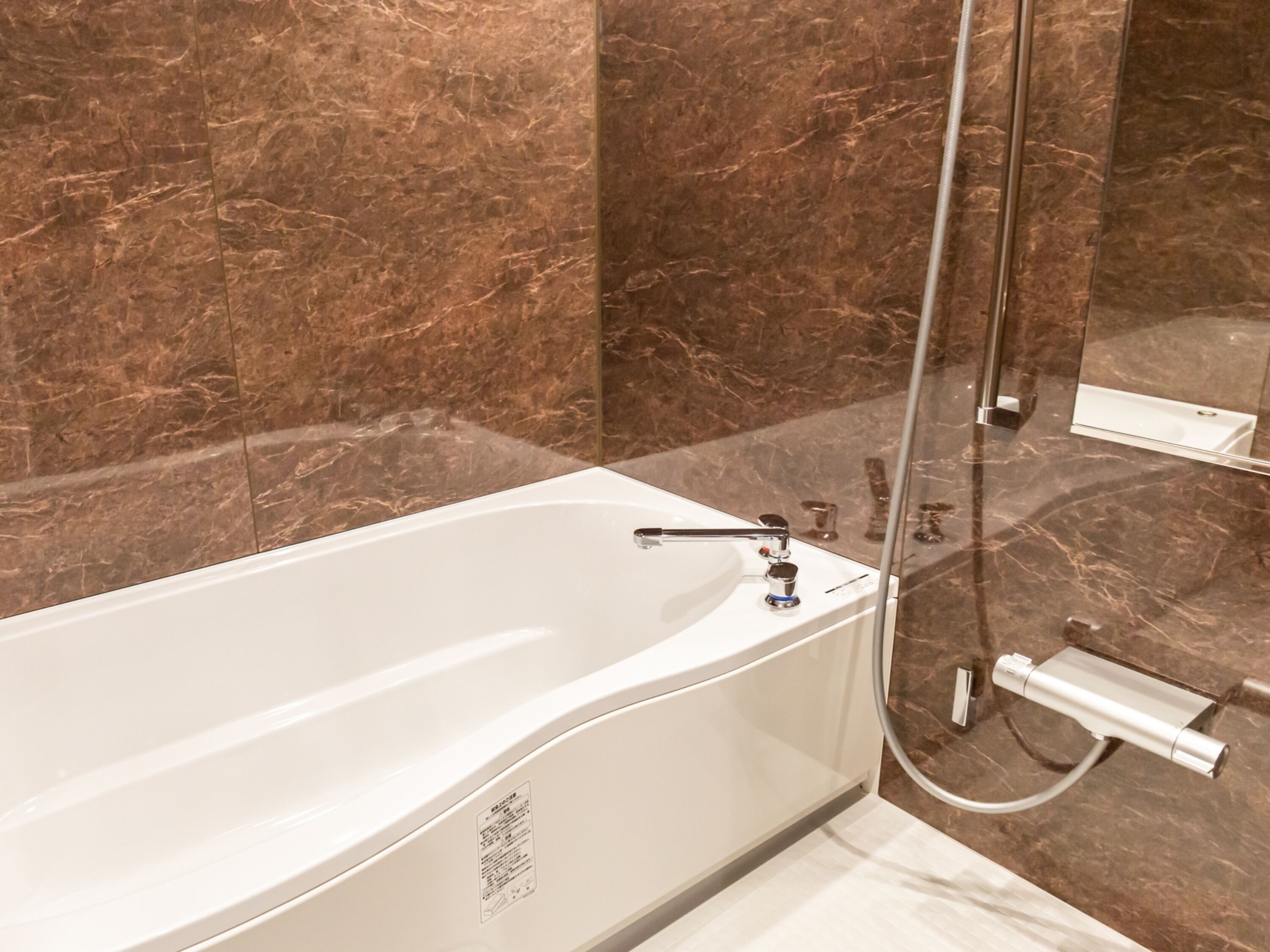 Une salle de bain moderne avec une baignoire blanche, une douchette à main et une cabine de douche en verre.