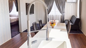 A modern hotel room with a long dining table, a sofa, and a TV mounted on the wall. - Paprika Hotel desu (Kisarazu)