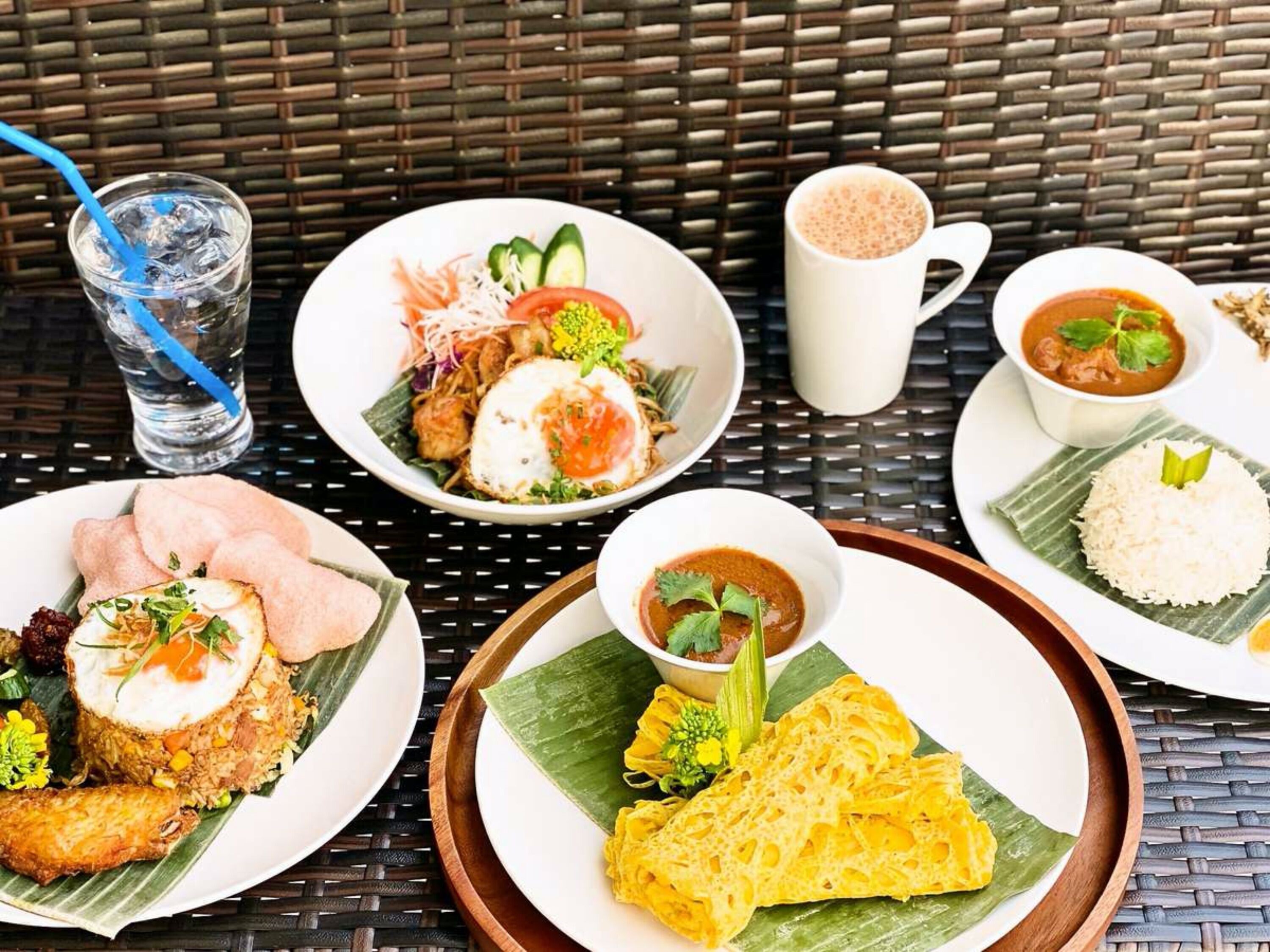 Una mesa dispuesta con diferentes platos, incluyendo arroz frito, un tazón de sopa y una taza de café.