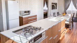 A modern kitchen with a central island, built-in oven, and microwave. - Paprika Hotel desu (Kisarazu)