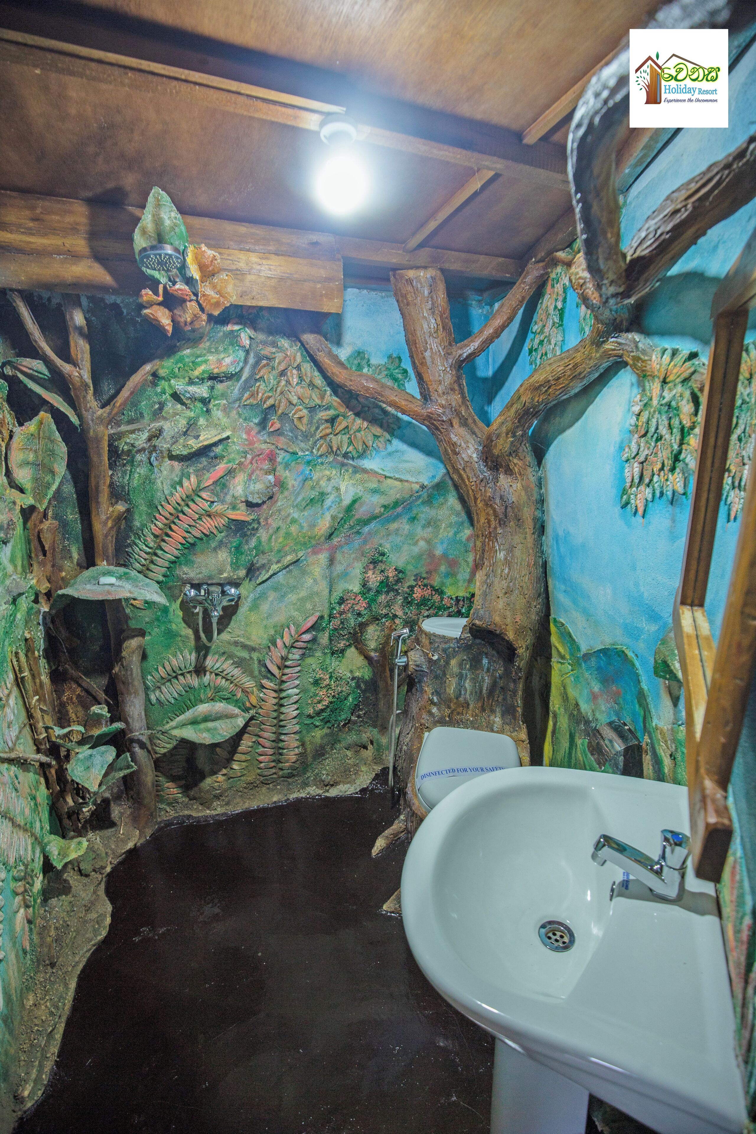 A bathroom with a tree-themed mural, a sink, and a mirror.