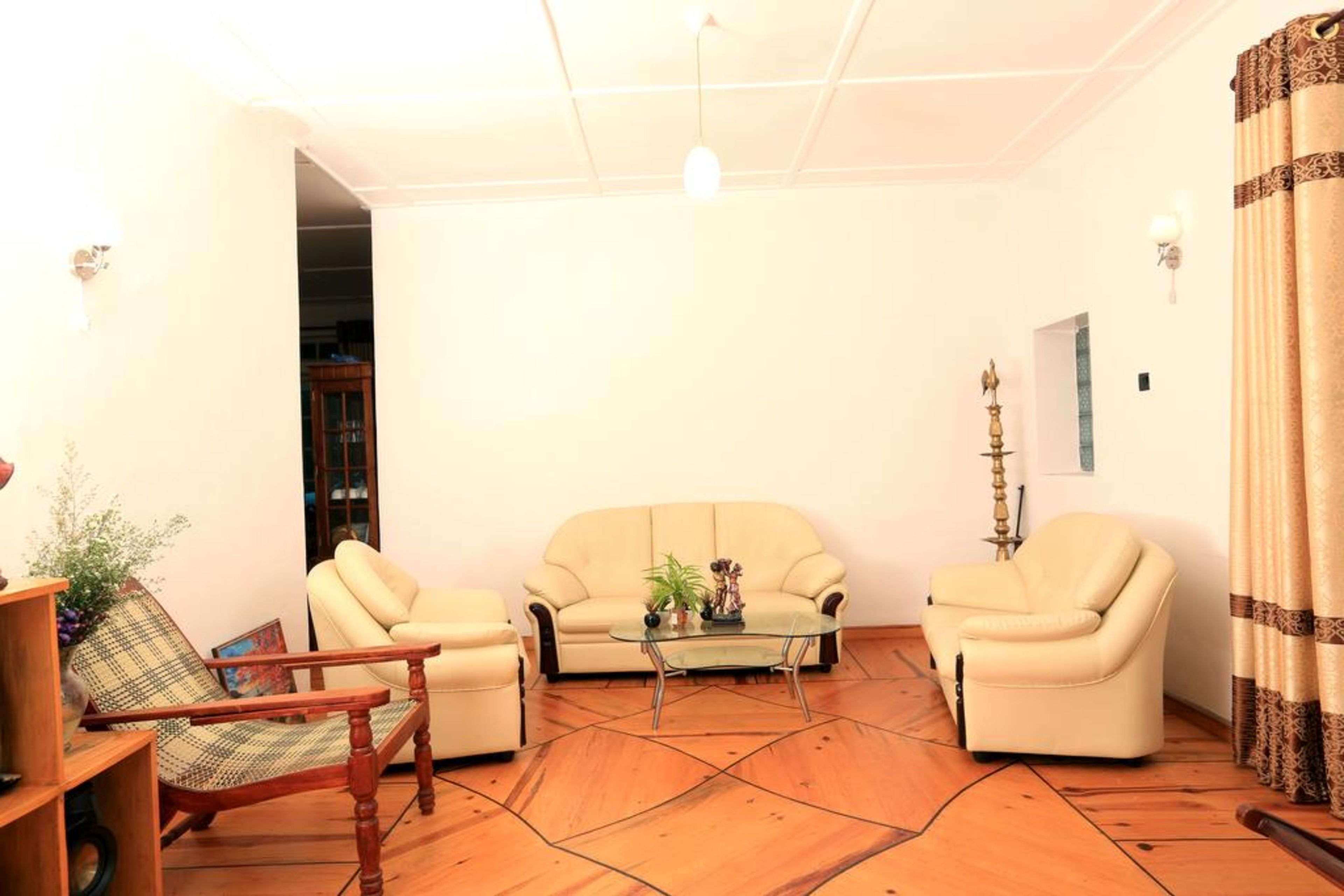 A living room with two beige sofas, a glass coffee table, and a wooden armchair.