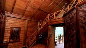 A wooden cabin interior with a staircase leading to an outdoor area, a fireplace, and a rustic decor.
