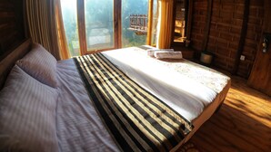 A bed with striped bedding, a window with curtains, and a brick wall.