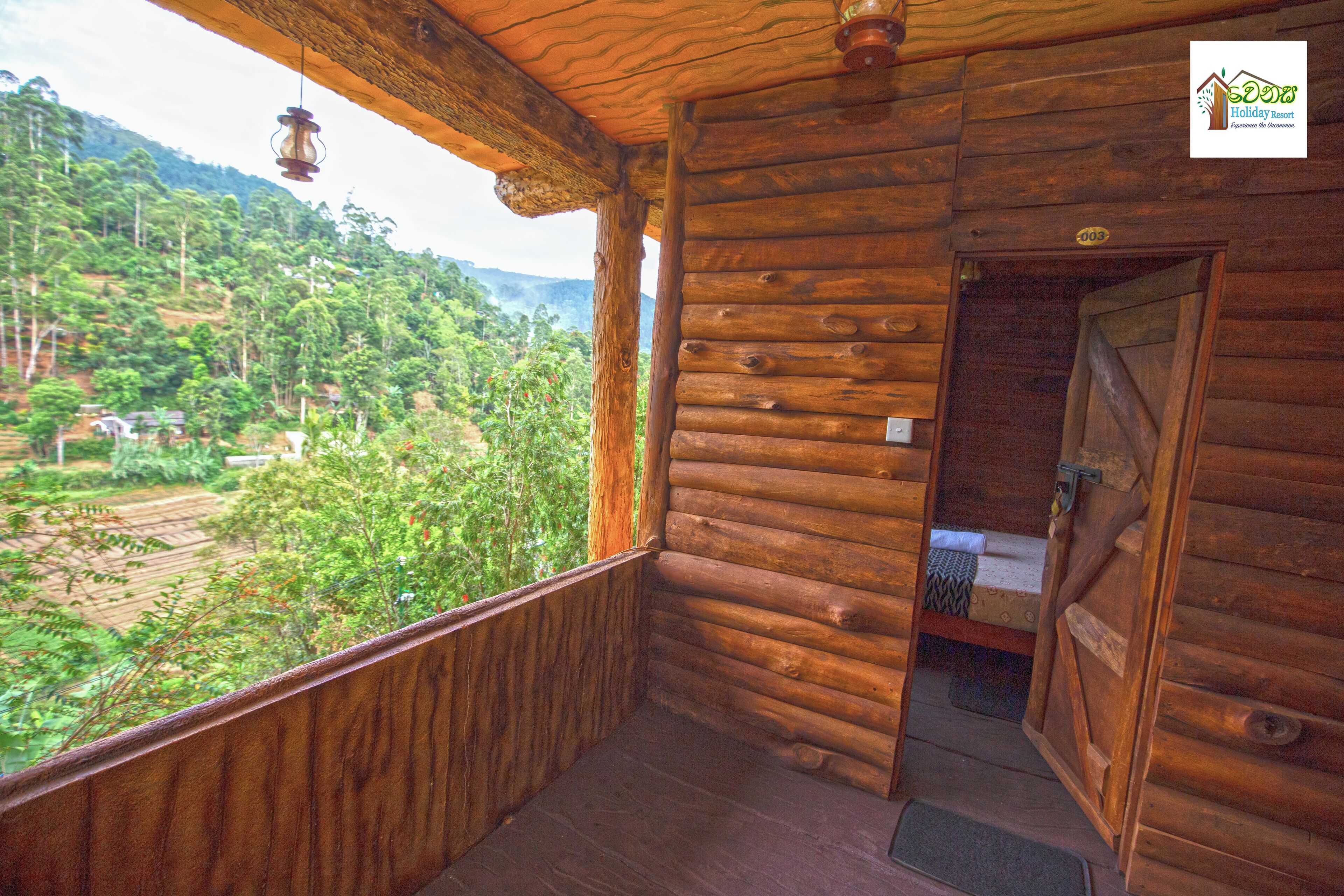 A wooden cabin with a balcony overlooking a lush green landscape.