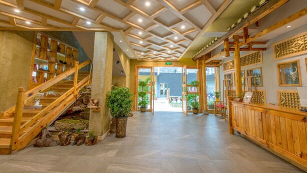 A wooden interior with a staircase, a reception desk, and a view of the outside. - Floral Hotel Fenghuang Huercaowu (Xiangxi)