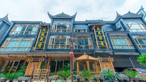 A traditional building with multiple stories, large windows, and wooden railings. - Floral Hotel Fenghuang Huercaowu (Xiangxi)