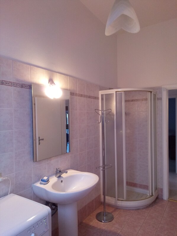 Un baño con lavamanos, espejo y cabina de ducha.