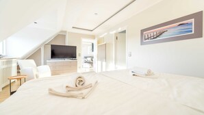 Et moderne hotelværelse med en stor seng, et fjernsyn, et skrivebord og et billede på væggen.